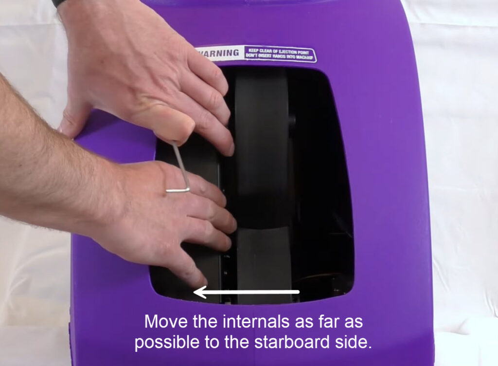 Hands moving the internal assembly fully toward the starboard (right) side of the machine opening